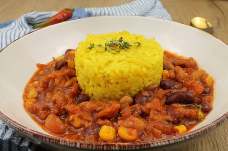 Ein Teller mit Chilli sin Carne, in der Mitte eine Portion gekochter Reis als Beilage.