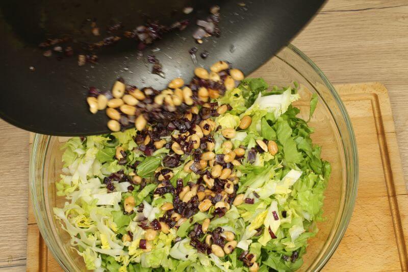 Erdnüsse und Zwiebel auf den Salat geben